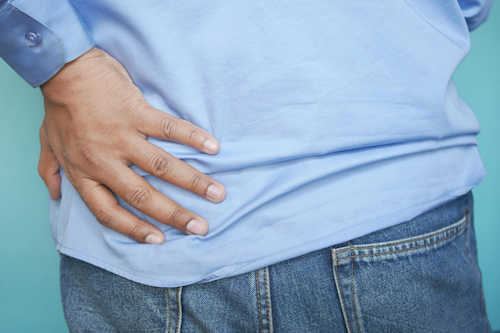 Person with left hand on left lower back